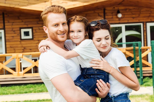 Happy Young Family Embracing Garden Wooden Cottage — Stock Photo, Image