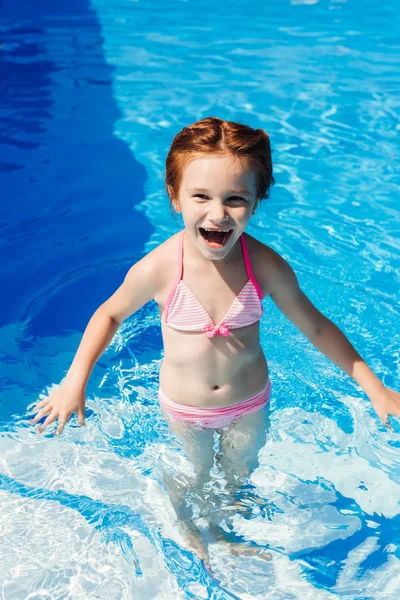 laughing little child in bikini in swimming pool