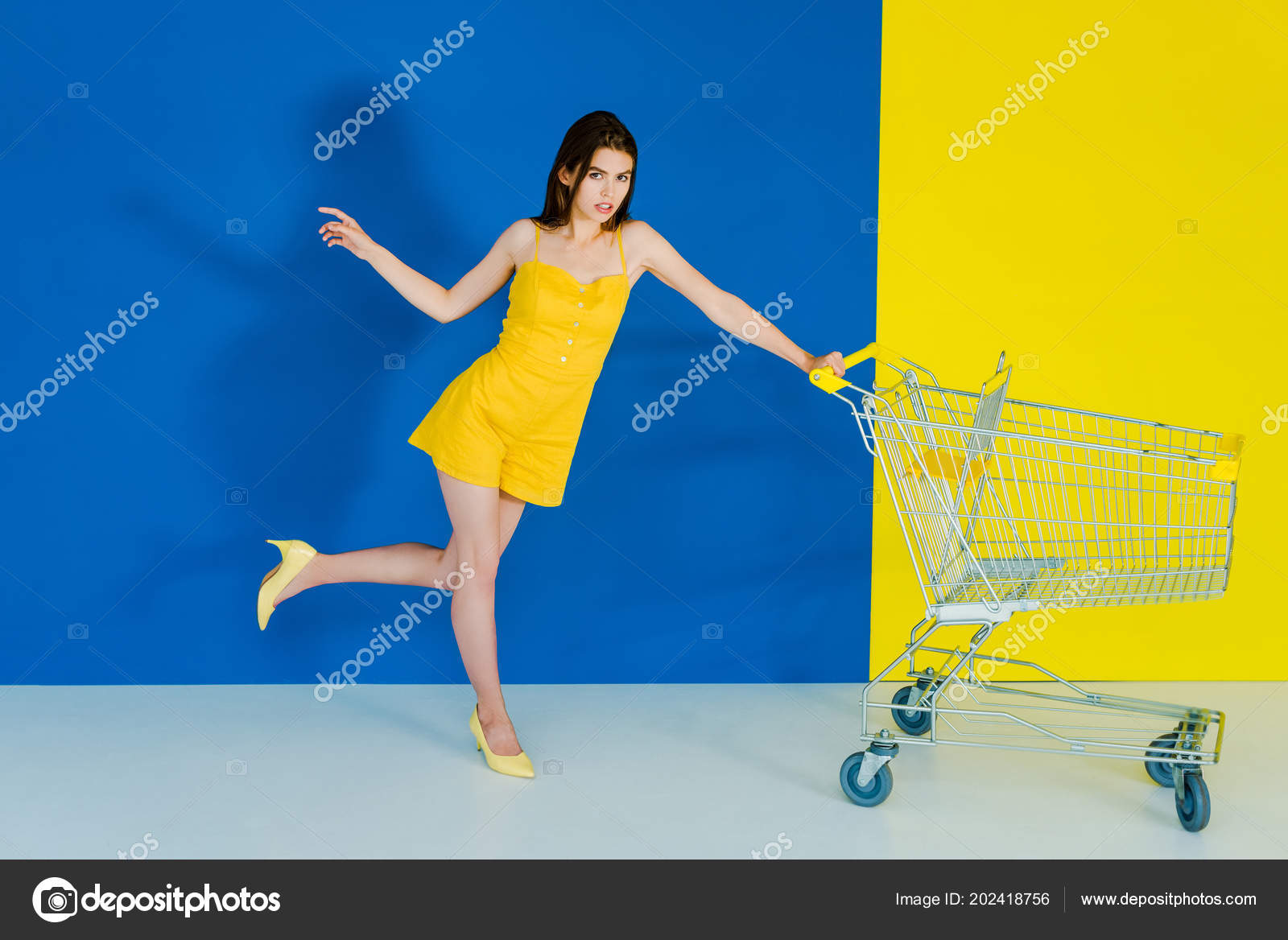 Female Fashion Model Pushing Shopping Cart Blue Yellow Background
