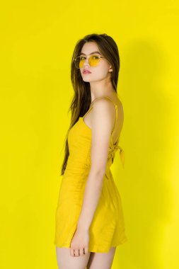Kadın moda model sarı elbise ve sarı zemin üzerine poz güneş gözlüğü