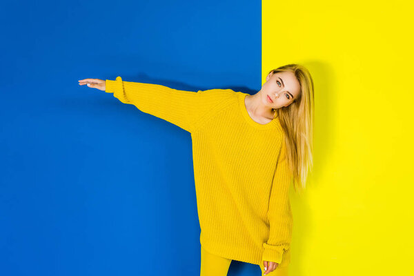 Attractive young girl posing in yellow clothes on blue and yellow background