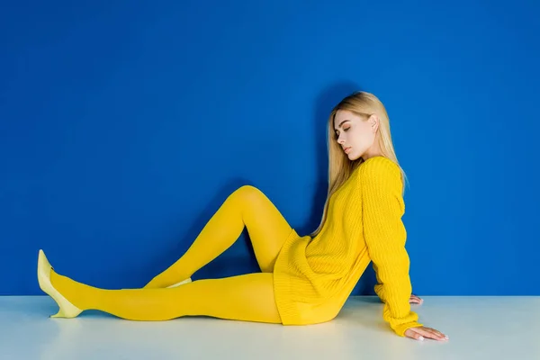 Elegante Mujer Rubia Vestida Amarillo Sentada Suelo Sobre Fondo Azul — Foto de Stock