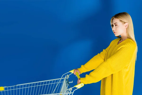 Attractive Young Girl Pushing Shopping Cart Blue Background — Free Stock Photo