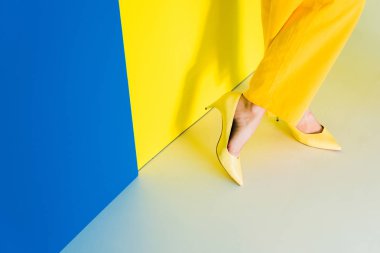 Bayan topuklu ayakkabı ayaklarda görünümünü mavi ve sarı zemin üzerine kırpılmış