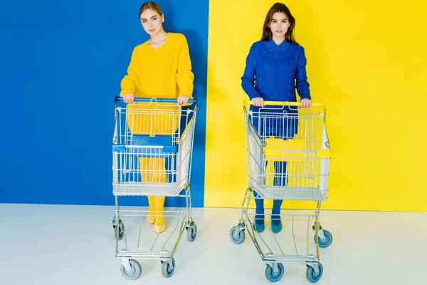 Attractive Young Girls Fashion Clothes Pushing Shopping Carts Blue Yellow — Stock Photo, Image