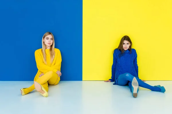 Modieuze Meisjes Zitten Vloer Blauwe Gele Achtergrond — Stockfoto