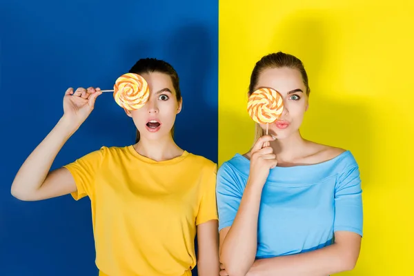 Vrouwelijke Maniermodellen Lollies Houden Blauwe Gele Achtergrond — Stockfoto