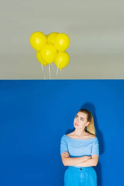 Mujer Rubia Triste Mirando Globos Bajo Techo Sobre Fondo Azul — Foto de stock gratis