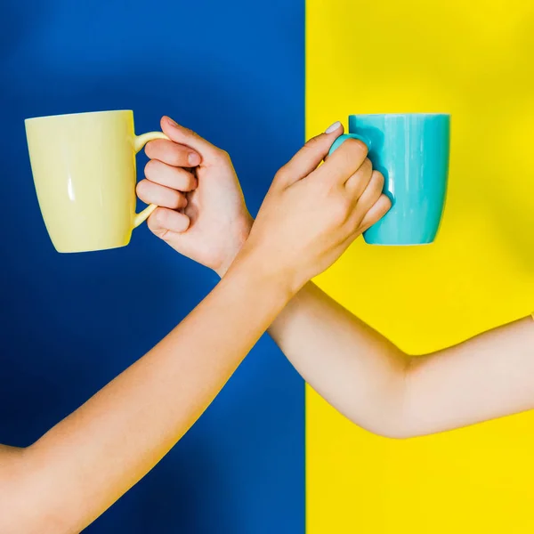 Bijgesneden Beeld Van Vrouwelijke Handen Met Cups Blauwe Gele Achtergrond — Stockfoto