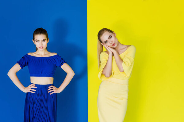 Attractive young girls in blue and yellow outfits posing on matching backgrounds