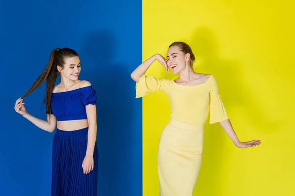 Beautiful Brunette Blonde Girls Blue Yellow Outfits Posing Matching Backgrounds — Stock Photo, Image