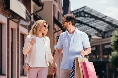 Elele ve alışveriş torbaları ile sokakta yürürken sevmek çift