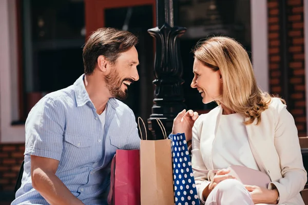 Feliz Pareja Sentado Con Bolsas Compras Banco Mirándose Uno Otro — Foto de stock gratis