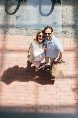 Çift güneş gözlüğü sokakta kameraya bakarak gülen, yüksek açılı görünüş