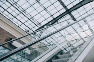 grey moving staircase with stairs and glass roof in shopping mall