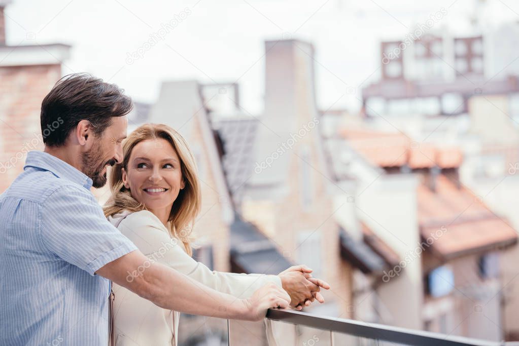 happy couple hugging on balcony and looking at each other