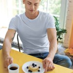 Portrait of pensive man sitting at table with breakfast at home