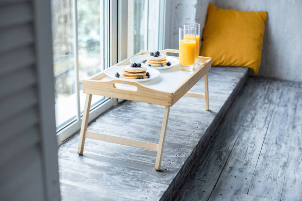 close up view of glass of juice and pancakes for breakfast on wooden tray at home