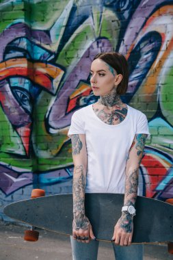 renkli grafiti ile duvara longboard tutan dövmeli genç kız 