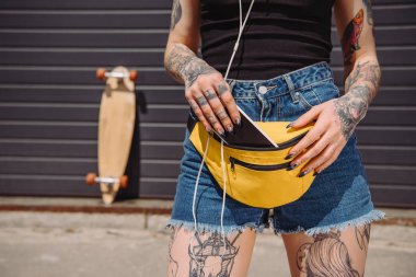 dövmeli kız bel çantasında boş ekran ile akıllı telefon koyarak görüntü kırpılmış 