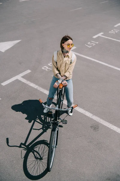 駐車場に自転車を持つスタイリッシュな女性のハイアングル  — 無料ストックフォト
