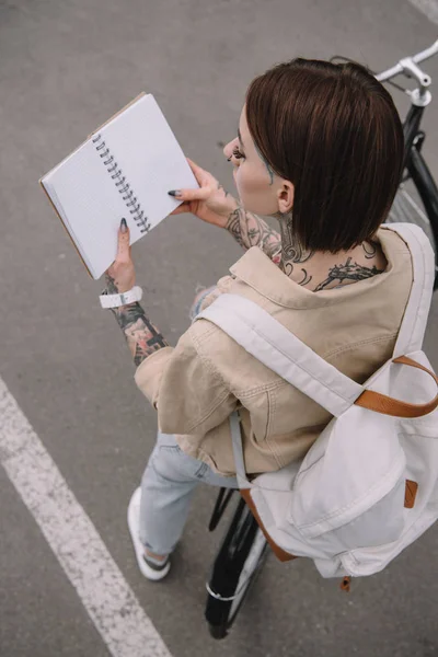 Vista Alto Ângulo Mulher Tatuada Elegante Segurando Notebook Branco Enquanto — Fotos gratuitas