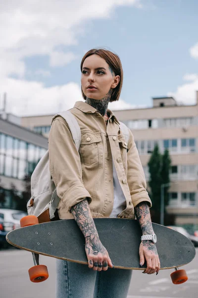 Stylish Tattooed Woman Looking Away Holding Longboard Street — Stock Photo, Image