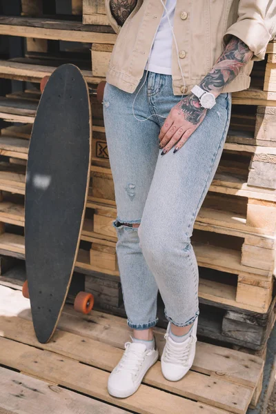 Oříznutý Obraz Tetované Ženy Stojící Skateboard Poblíž Dřevěné Palety — Stock fotografie zdarma