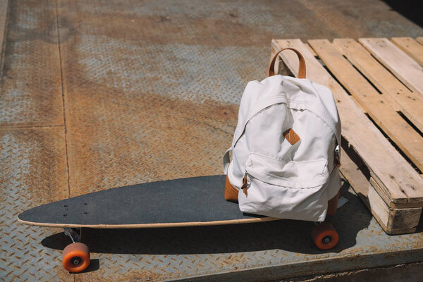 close up view of backpack on skateboard near wooden pallet 