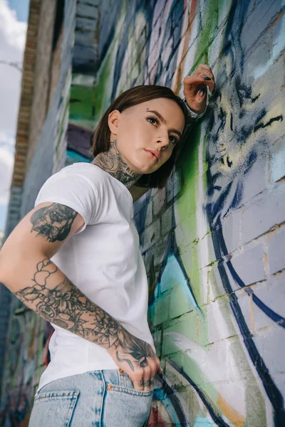 Baixo Ângulo Vista Menina Tatuada Elegante Posando Perto Parede Com — Fotografia de Stock Grátis