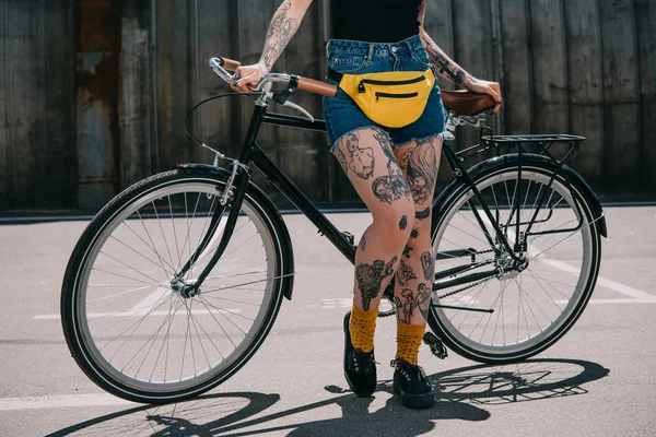 トリミングされた画像通りで自転車で腰 Bagstanding とスタイリッシュな刺青の女の子の — ストック写真