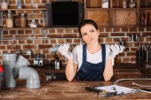 Nachdenkliche junge Installateurin mit Plastikrohren in der Küche
