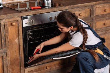Genç repairwoman tornavida ile fırın tamiri