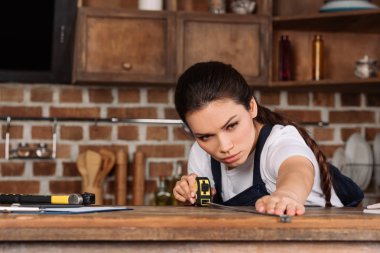 kendine güvenen genç repairwoman mutfak masasında bant ile ölçme