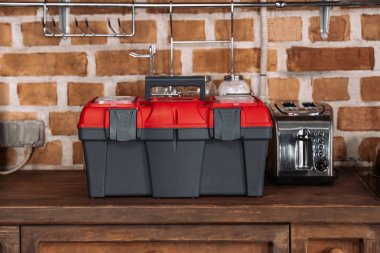 close-up shot of toolbox standing on kitchen table with toaster in front of brick wall clipart