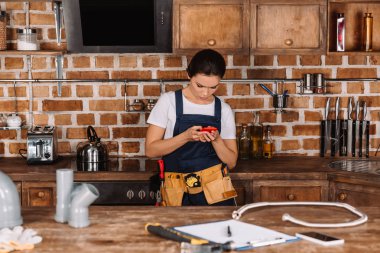 çekici genç kadın tesisatçı mutfağa Smartphone kullanarak