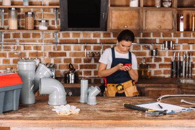 güzel genç kadın tesisatçı mutfağa Smartphone kullanarak