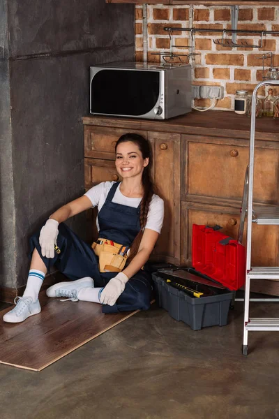 Szczęśliwa Młoda Repairwoman Relaksujący Siedząc Podłodze Kuchni — Darmowe zdjęcie stockowe