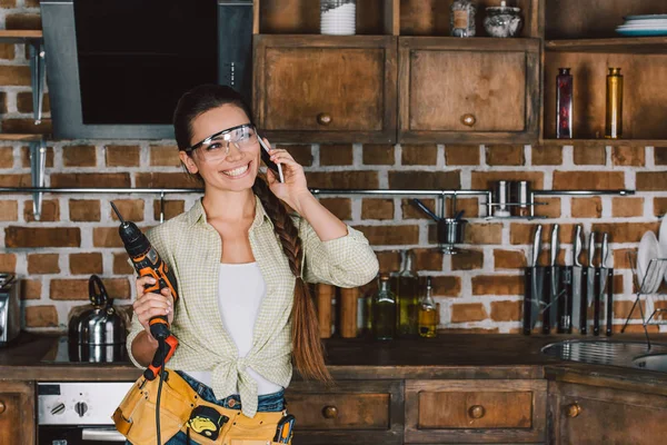 Szczęśliwy Repairwoman Młodych Okulary Ochronne Wiertarka Rozmawia Przez Telefon — Zdjęcie stockowe