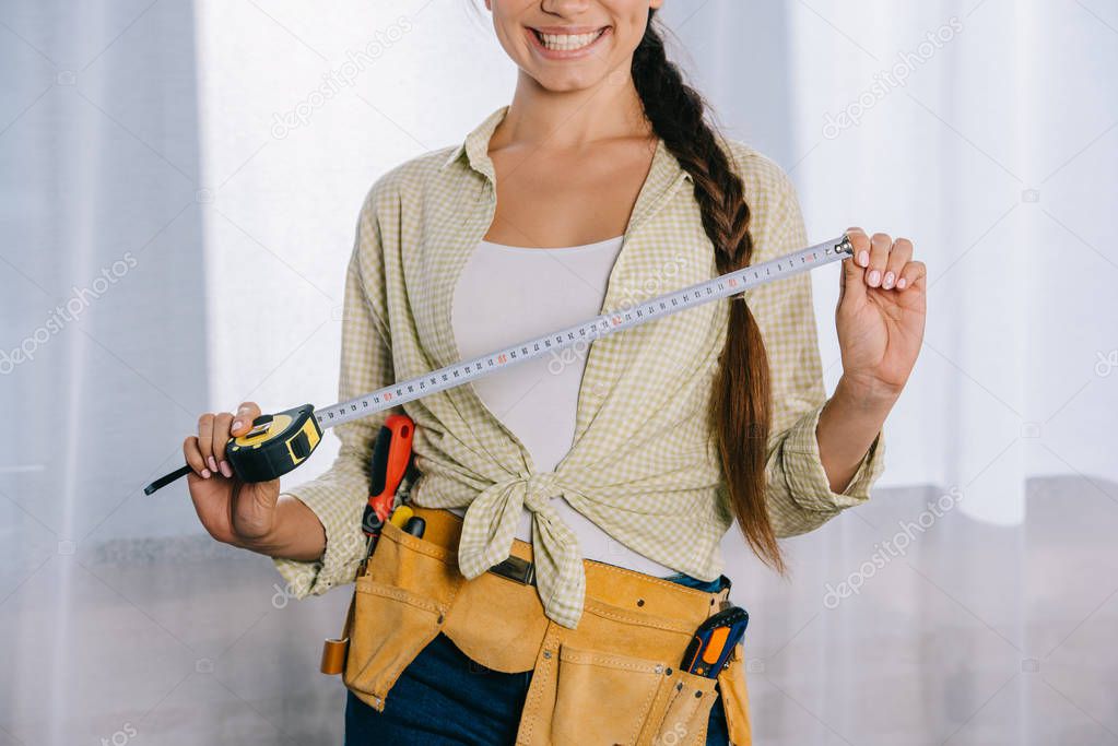 cropped shot of smiling young repairwoman with measuring tape