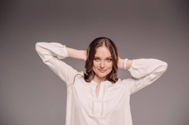 gülümseyen çekici kadın baş üzerinde izole gri arka plan arkasında geniş silah ile poz 