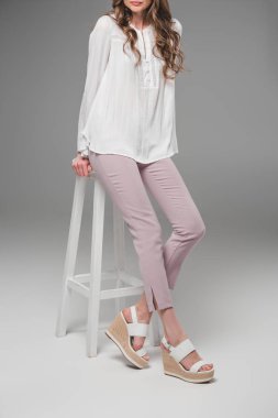 gri arka plan üzerinde sandalye üzerinde oturan zarif kadın resim kırpılmış 