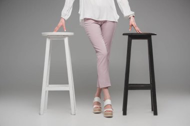 cropped image of female model standing between chairs on grey background  clipart
