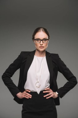 gri arka plan üzerinde izole kalça üzerinde ciddi işkadını gözlük ile ayakta eller 