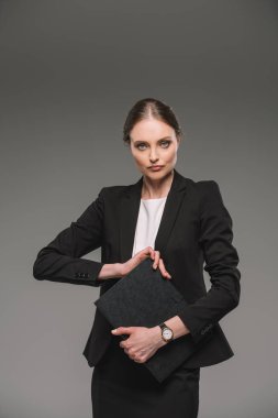 gri arka plan üzerinde izole ders kitabı tutarak ciddi iş kadını 