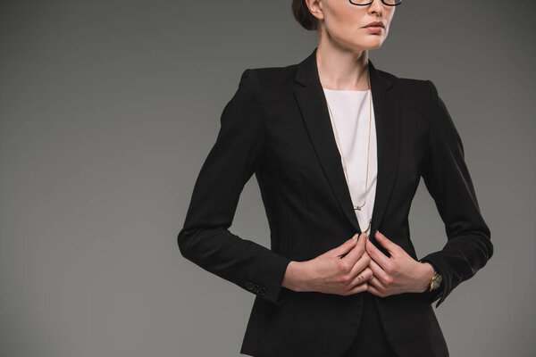 обрезанный образ серьезной предпринимательницы, изолированной на сером фоне
 