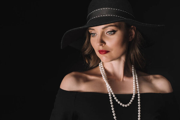 beautiful woman in black straw looking away isolated on black background 