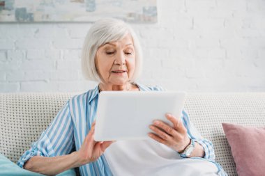 evde kanepede tablet kullanarak kadın kıdemli portresi
