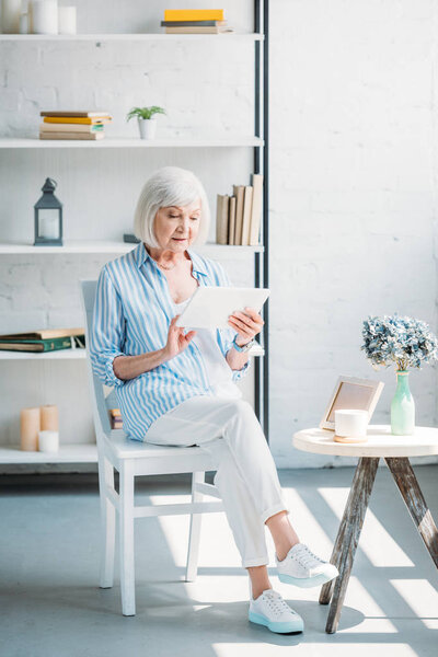 stylish senior woman using tablet at home