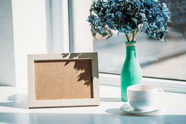 boş fotoğraf çerçevesi, kahve ve buket HORTENSIA çiçek vazoda pencere görünümünü kapat